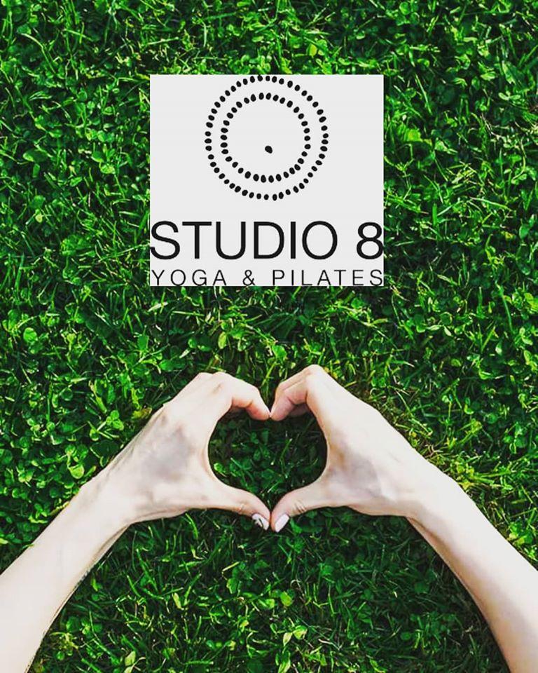 Twee handen maken een hart boven klavertjes vier met het logo van Studio 8 Yoga & Pilates